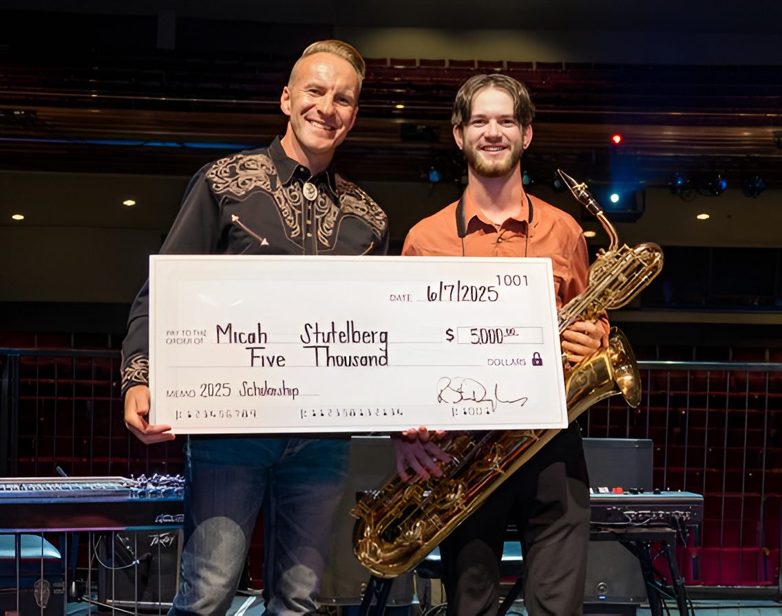 Two men with a large check and saxophone.