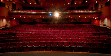 Empty theater with red seats and spotlight.
